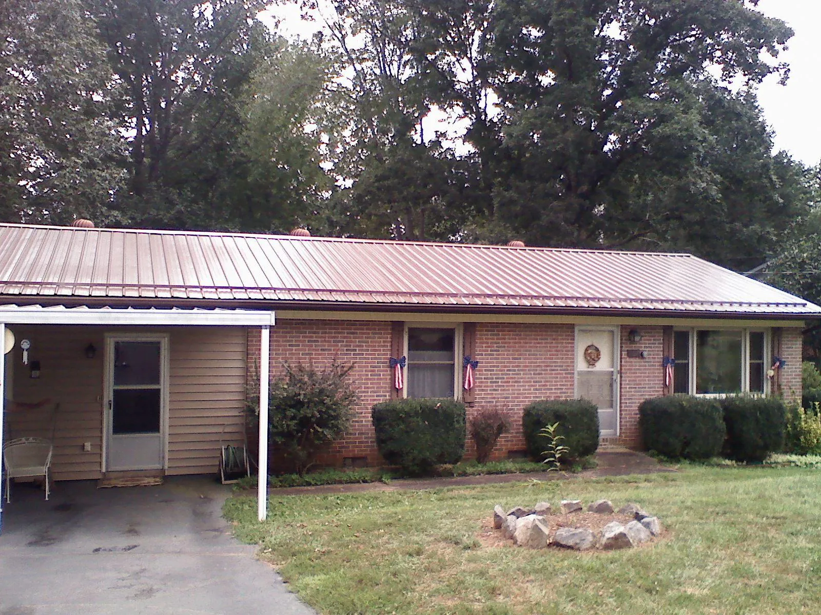 Bronze metal roof and carport on a brick ranch home — Roof Repair work by our crew in Lucas